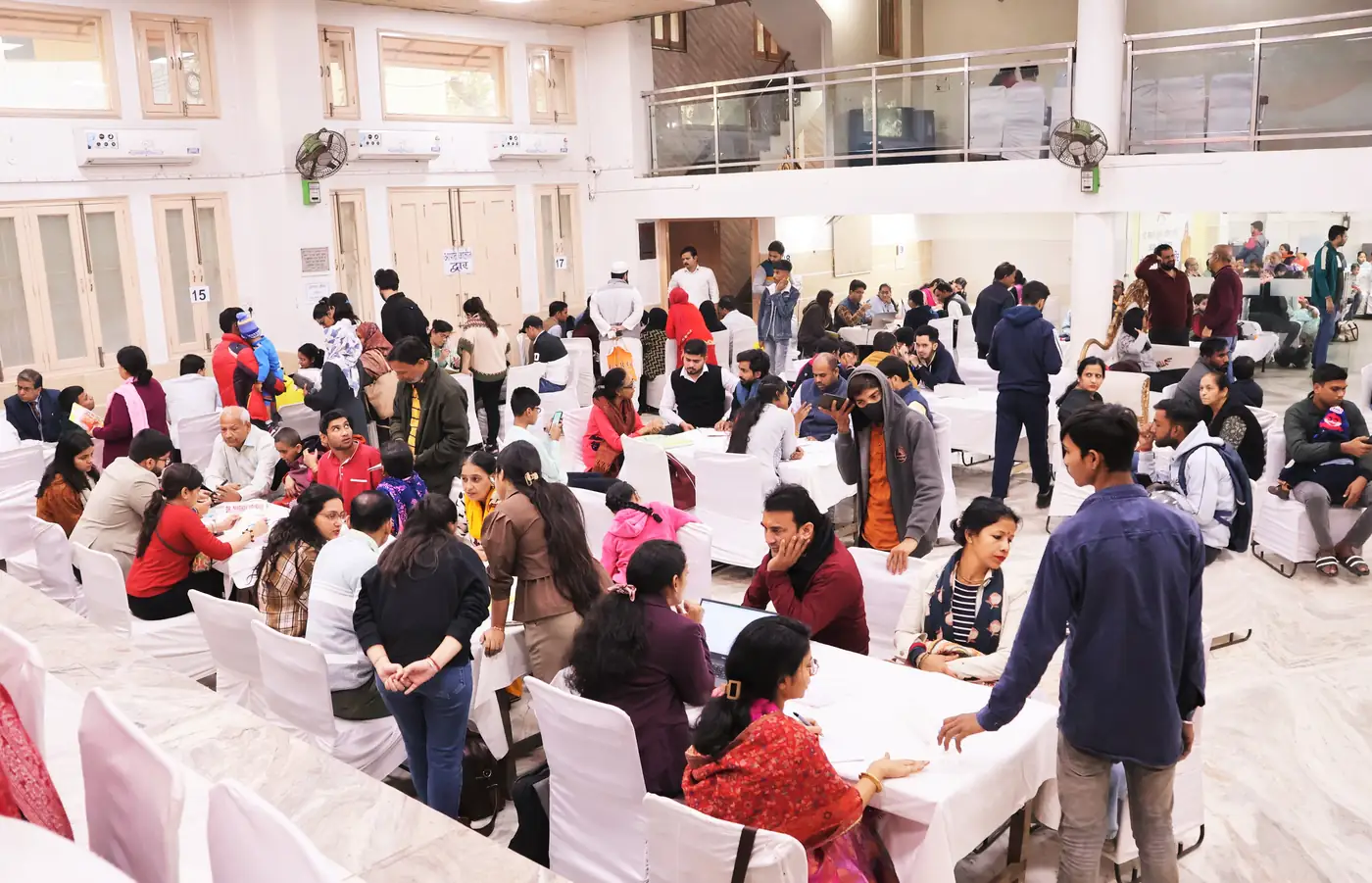The main hall on a camp day, with doctors at numbered tables and families waiting